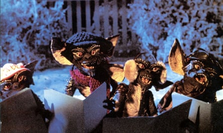 A group of four small, scary-looking creature, green with scaly skin, pointed ears, and poiny teeth, are partly lit in a snowy yard.