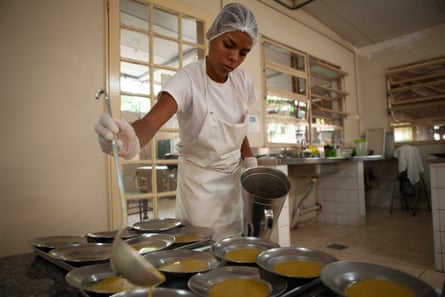 Uma mulher vestindo roupas de chef serve sopa em tigelas