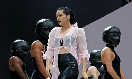 Rosalía with a group of dancers wearing black motorbike helmets.