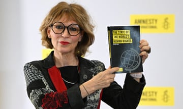 A middle-aged woman holds up a report that says: 'The state of the world's human rights' with the Amnesty candle and barbed-wire logo behind her