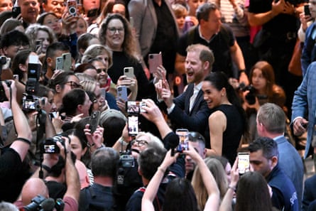 Prince Harry and Meghan react to a crowd of people taking photos of the couple on their phones