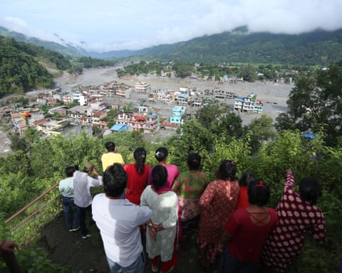 A crowd of people look into a flooded valley.