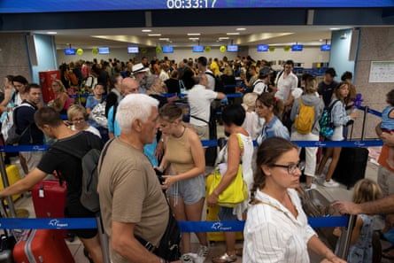 Turyści ustawiają się w kolejce przy stanowiskach odprawy, czekając na odlatujące samoloty na lotnisku na Rodos, po ewakuacji po ogromnym pożarze na wyspie.