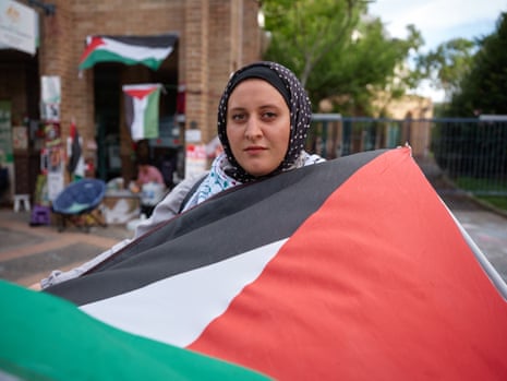 Yusra Metwally, a Solicitor and Senior Policy Officer, stands outside PM Anthony Albanese's office in Marrickville drapped in a Palestinian flag, 2024. Sydney. Australia
