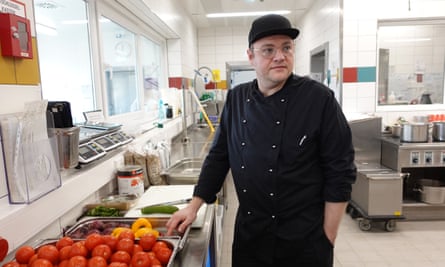 A chef standing by containers of vegetables.