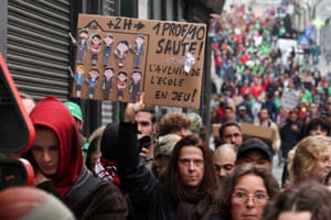 A protester in a crowd holding a placard in French that reads ‘The school’s future at stake!’