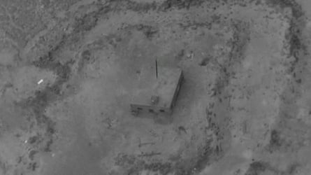 Black and white aerial image of a small building surrounded by barren land