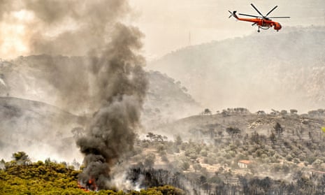 A firefighting helicopter drops water as a wildfire hits at Panorama settlement near Agioi Theodoroi