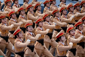 Dozens of Vietnamese female police officers wearing brown uniform with red trimmed hats march in unison at a parade in Ho Chi Minh City.