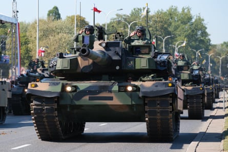 Konwój czołgów przejeżdża autostradą w Warszawie. Na czołgach powiewają polskie flagi.