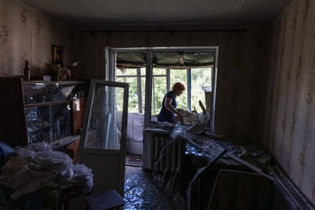 A woman clears rubble from her home.