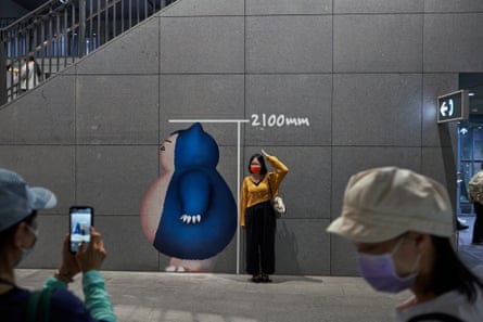 Ένας θαυμαστής των Pokémon ποζάρει δίπλα σε ένα cutout του Snorlax.