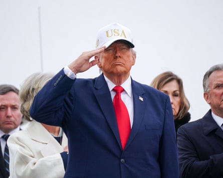 Donald Trump gives a salute wearing a USA baseball cap