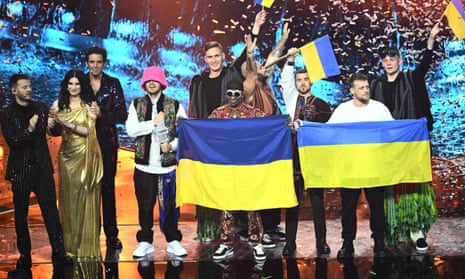 Eurovision hosts onstage with celebratory members of the Ukrainian band Kalush Orchestra 
