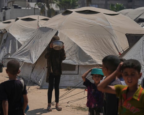 Displaced Palestinians wait for donated food at a community kitchen in Gaza City, northern Gaza Strip, Tuesday, 22 July 2025.