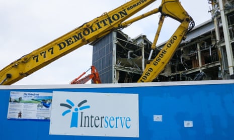 Yellow demolition crane indicates towards Interserve sign