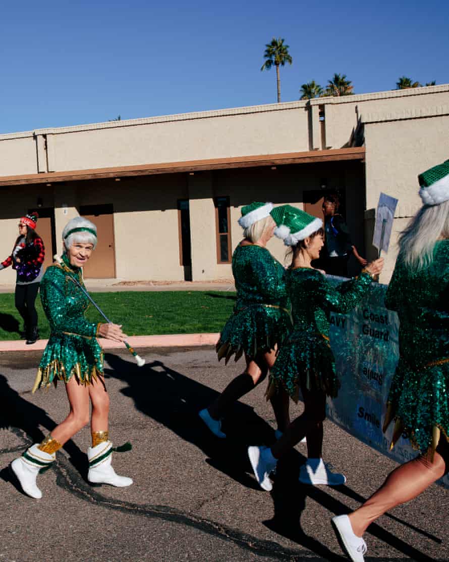 Members of the Sun City Poms cheerleading group walk down the street before the Christmas in the Park holiday parade in Litchfield Park, Arizona, December 11 2021