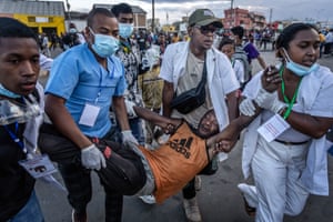 A group of medics carry a man who has had a drip fitted along a street