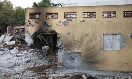 A damaged building with bullet holes and a gaping hole from a blast at one end