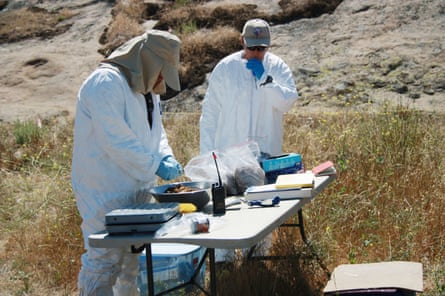 two people in white protective suits at a table outdoors