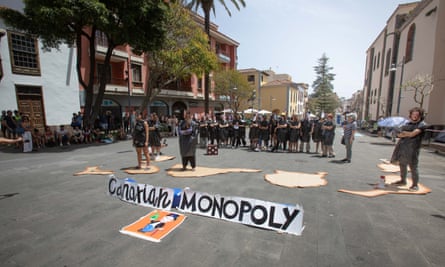 People stand blocking the street wearing masks that say ‘Canarian Monopoly’
