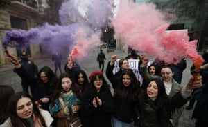 Activists hold flares issuing purple and red smoke