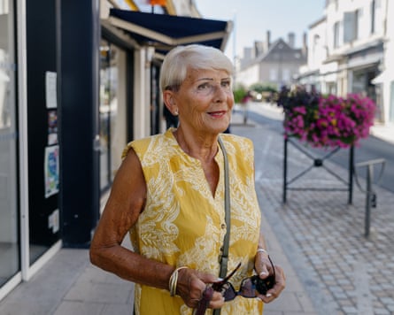 A woman on the street holding a pair of sunglasses and wearing a shoulder bag