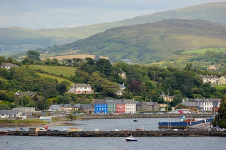 pretty colouful harbour town backed by green wooded hillside