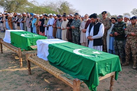 Muslim worshippers pray over two coffins covered in Pakistani flags.