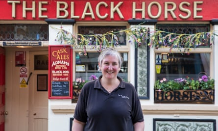 A woman stands in front of a pub called the Black Horse