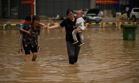 People wade through a flooded street following heavy rain in Zhengzhou, in China’s Henan province