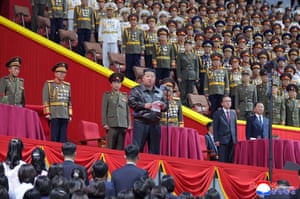 The North Korean leader, Kim Jong-un, addresses a people at a stadium, flanked by rows of military officers