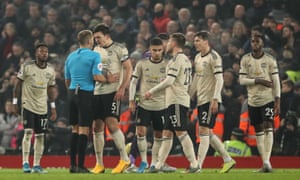 Manchester United players surround the referee.