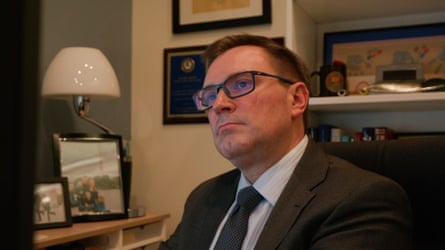 a man in a suit looks forward while seated
