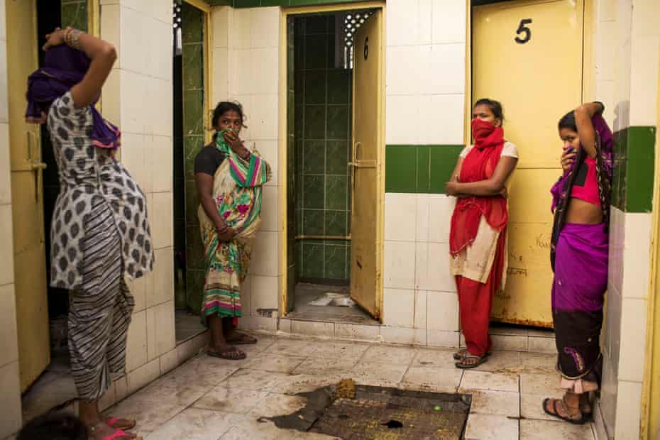 In a community toilet building in Delhi, four women wait for the one working stall to become free