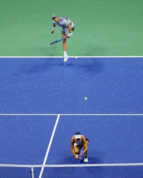 Jack Draper fires down a serve as playing partner Jessica Pegula crouches near the net.