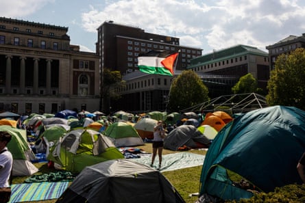 A person waves the Palestinian flag in the middle of an encampment on a campus lawn