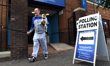 A man accompanied by his dog laughs as he leaves a polling station in Belfast after voting in the EU referendum.