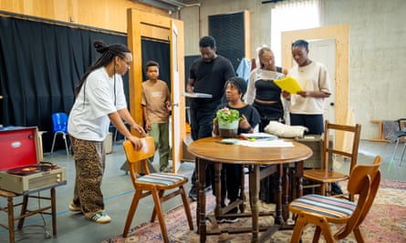 Craig and the cast stand around wooden kitchen table during rehearsals