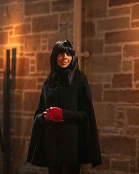 Claudia Winkleman wearing a black coat and red gloves