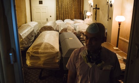 A funeral director stands in front of empty caskets for victims of Covid-19 stored in a room at a funeral home in Queens, New York, 29 April 2020.