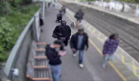 Simon Levy walking along an outdoor train platform among other people