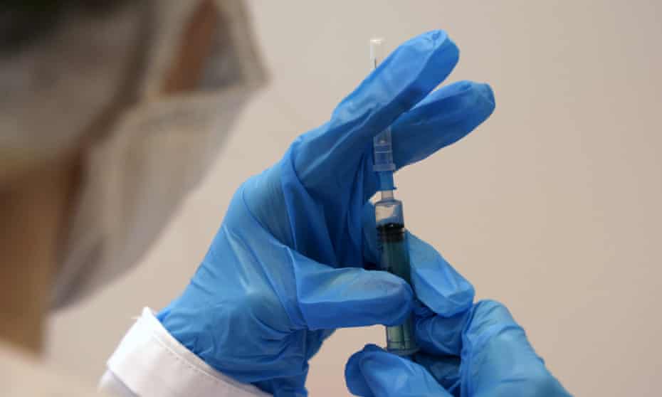 A medical worker holds a syringe.