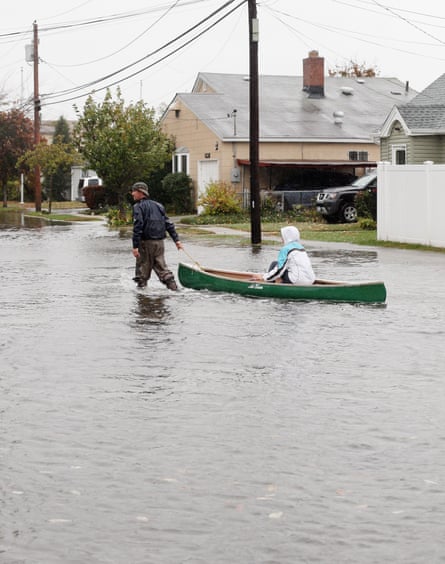 A resident pulls a woman in a canoe down 6th Street as high tide, rain and winds flood local streets on October 29, 2012 in Lindenhurst, New York.
