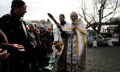 An Orthodox priest sprinkles people with water  