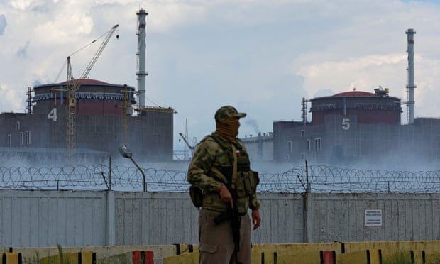 A serviceman with a Russian flag on his uniform stands guard near the Zaporizhzhia nuclear power plant