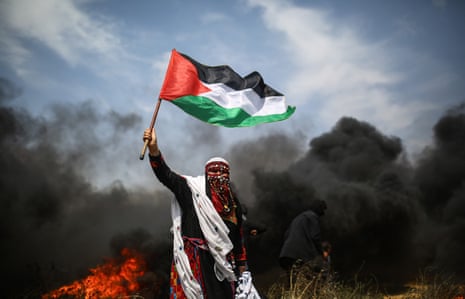 A man holds a Palestinian flag during protests at the Gaza-Israel border