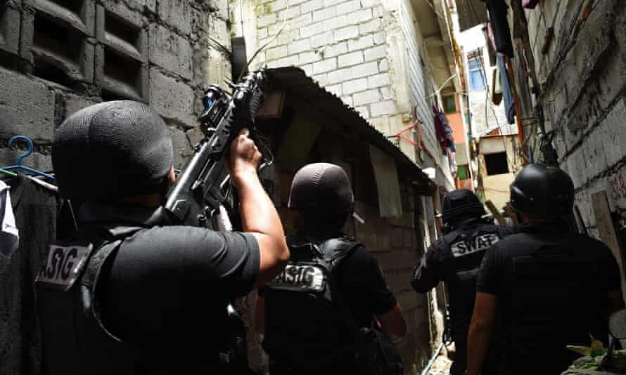 A Philippine police Swat team takes position as they serve a search warrant in relation to drugs at an informal settler house in Pasig City, suburban Manila.