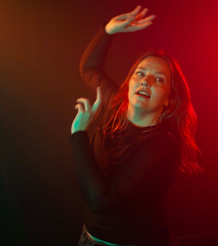 The comedian Kate Dehnert flails against a dark background.