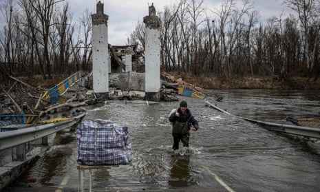 A resident of Bohorodychne crosses the Siversky Donets river at a destroyed bridge to retrieve bread from the other bank